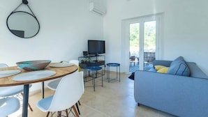 A modern living room with a sofa, TV, dining table, and chairs.