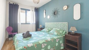 A bedroom with a bed, a nightstand, a chair, and a window with curtains. - Nid du 5ème - Proche Bd Baille - Métro et commerce (Marseille)