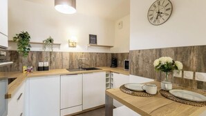 A modern kitchen with white cabinets, a wooden countertop, a sink, and a clock on the wall. - La Terrasse de Duranne - Accès rapide TGV Aéroport (Aix-en-Provence)