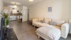 A modern living room with a sofa, a coffee table, and a TV. There is a kitchen in the background with a dining area. - La Terrasse de Duranne - Accès rapide TGV Aéroport (Aix-en-Provence)