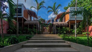 A pathway leading to a building with a thatched roof, surrounded by lush greenery and palm trees. - Tregua (Bacalar)