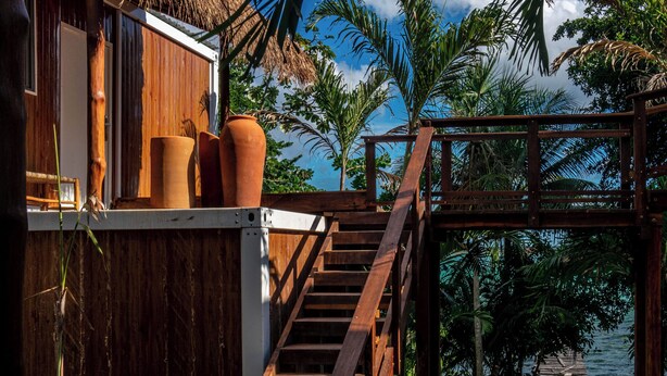 A wooden staircase leading to a beach area with a thatched-roof building and tropical plants. - Tregua (Bacalar)