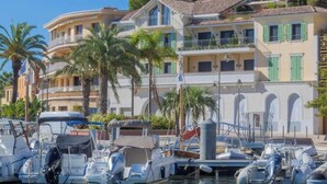 Un port de plaisance où sont amarrés plusieurs bateaux, entouré d’immeubles à plusieurs étages dotés de balcons et de volets verts.