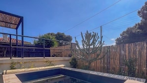 A rectangular swimming pool with a tiled edge, surrounded by a wooden fence and some vegetation. - Studio Terra'ciel - Proche calanques - Piscine (La Ciotat)