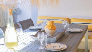 A dining table set with plates, glasses, and a bottle of white wine. - Studio Terra'ciel - Proche calanques - Piscine (La Ciotat)