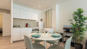 Una cocina moderna con armarios blancos, una mesa de comedor con platos color aguamarina y una planta en maceta.