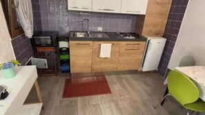 Une cuisine de taille réduite, avec des meubles de rangement en bois, un évier et un petit réfrigérateur.