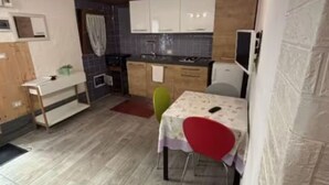 Une cuisine compacte avec des meubles en bois, un évier et un coin repas comprenant une table et des chaises.