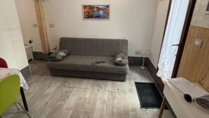 Une petite pièce meublée, comprenant un canapé, une table et une chaise.