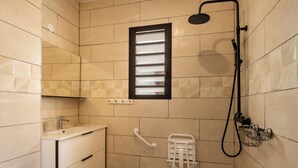 Ein Badezimmer mit einem weißen Waschbecken, einer Handbrause, einem Handtuchhalter und einem Fenster mit Jalousien.