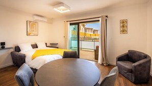 Ein Hotelzimmer mit Bett, einem Esstisch und einem Balkon mit Blick auf Gebäude.