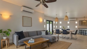 Een moderne woonkamer met een bank, salontafel en een eethoek.
