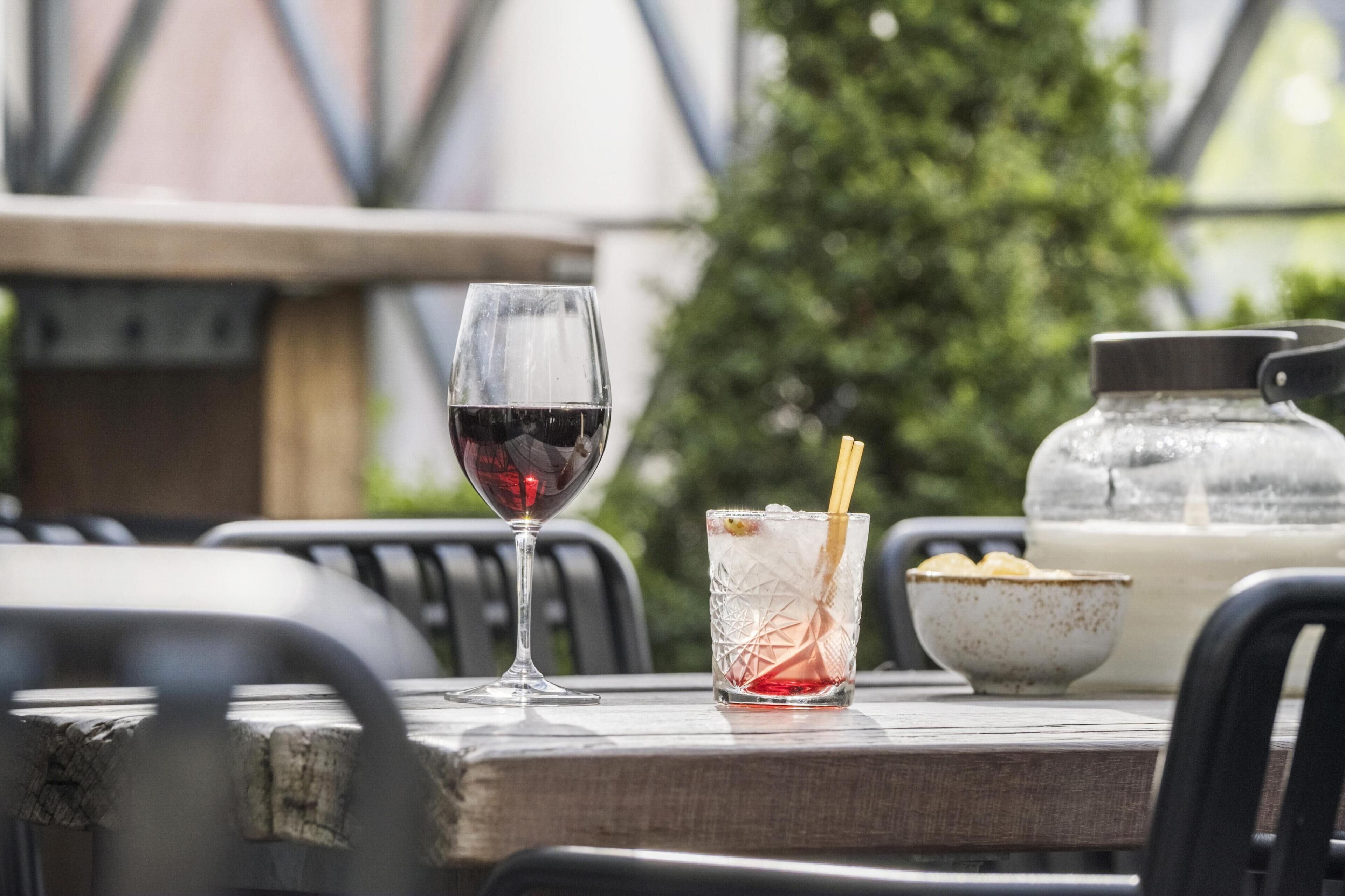 A table with a wine glass, a glass with a straw, and a bowl of chips.