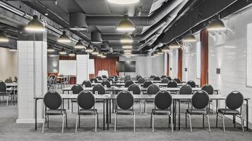 A conference room with tables and chairs, overhead lighting, and visible ductwork.
