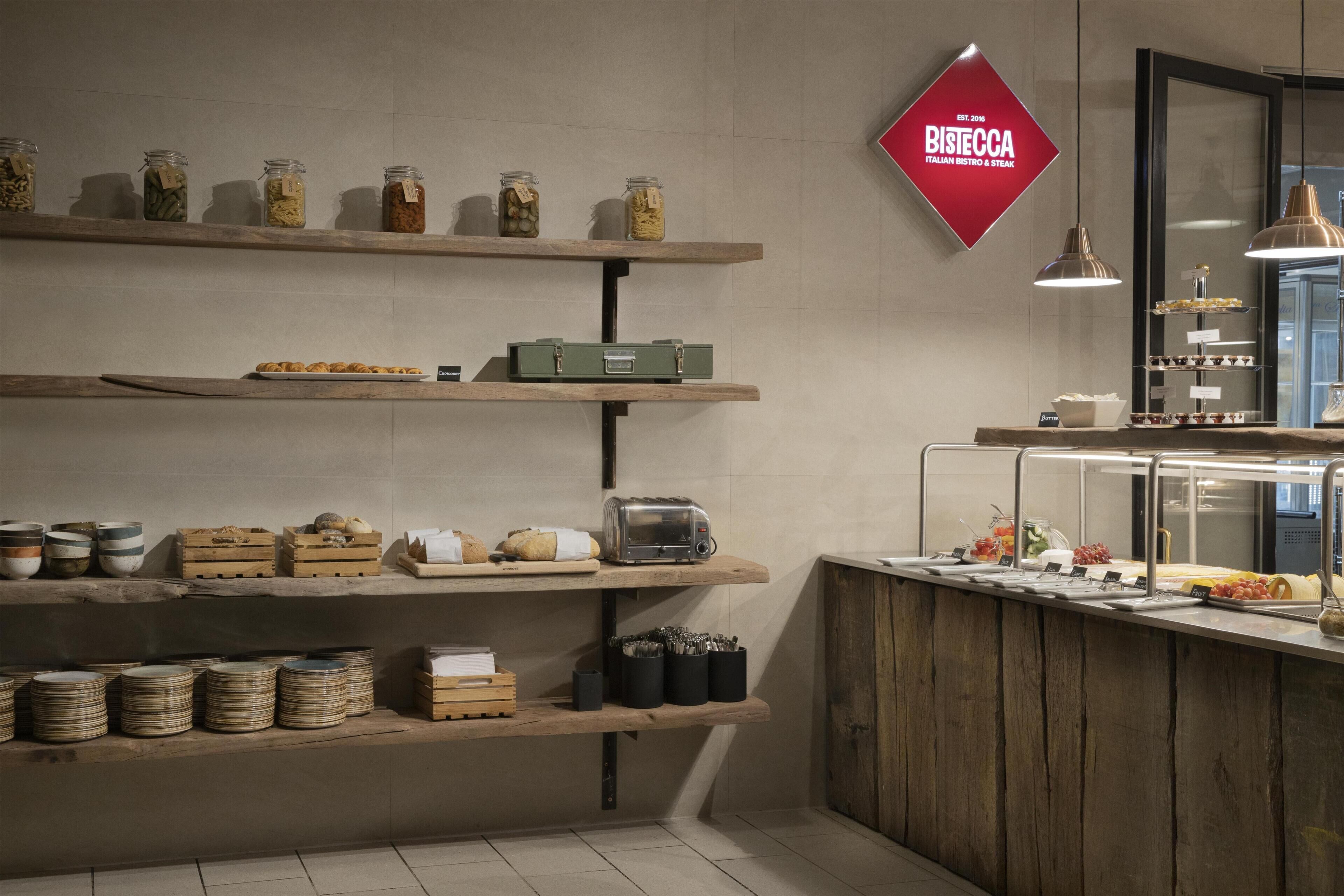 A breakfast bar with jars of food, a toaster, and a sign for Bistecca Italian Bistro & Steak.