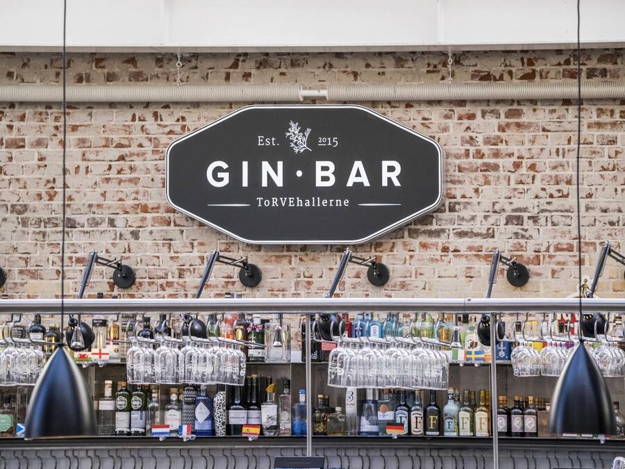 Un bar con un letrero que dice 'GIN BAR' y un fondo de pared de ladrillo.