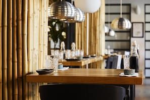 A restaurant interior with bamboo walls, wooden tables, and hanging pendant lights. - Villavejle Hotel, BW Signature Collection (Vejle)