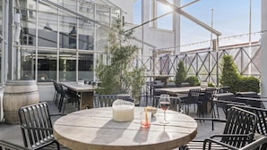 An outdoor patio with round tables, chairs, and a glass enclosure.