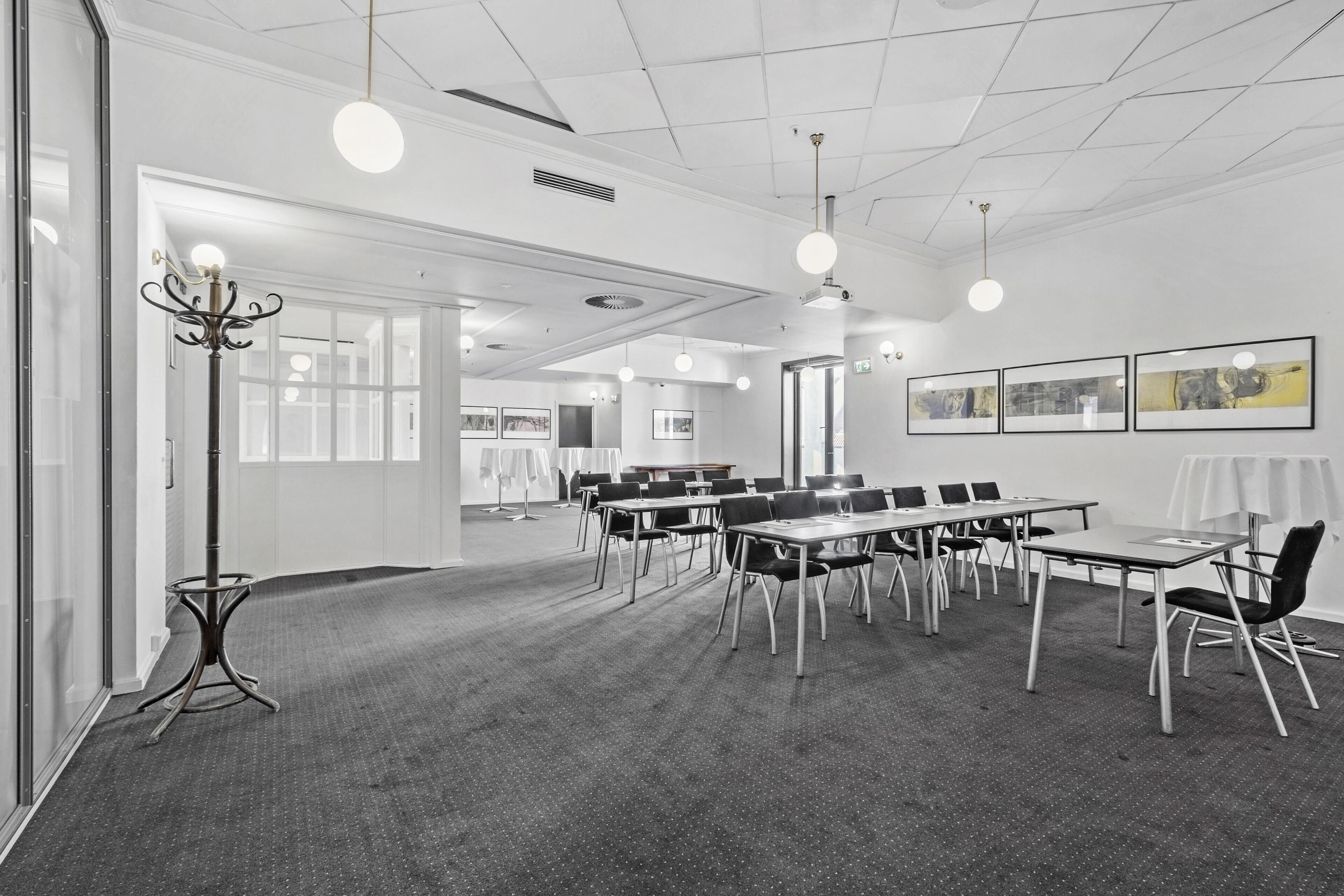 A conference room with tables, chairs, and pendant lighting.