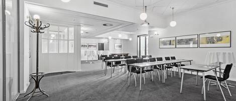 A conference room with tables, chairs, and pendant lighting.