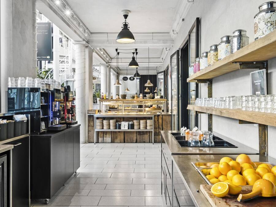 A modern kitchen with a central island, a coffee machine, and a variety of kitchenware on shelves.