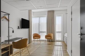 A modern hotel room with a wooden desk, two chairs, a flat-screen TV, and large windows with curtains. - Villavejle Hotel, BW Signature Collection (Vejle)