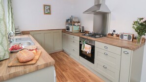 A compact kitchen with a sink, microwave, stove, and wooden countertop.
