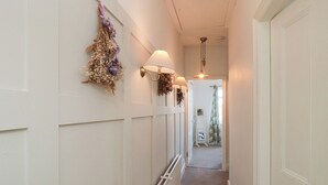 A narrow hallway with white walls, a radiator, and two wall-mounted lamps.
