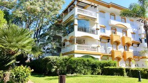 Un immeuble à plusieurs étages, doté de balcons et entouré de verdure et d’arbres.