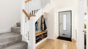 A staircase with a wooden handrail leading to a landing with a shoe rack and coat storage. - Family Friendly 3 Bed Home - Pass the Keys (Leamington Spa)