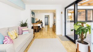 A modern living room with a sofa, a dining area, and a large potted plant. - Family Friendly 3 Bed Home - Pass the Keys (Leamington Spa)