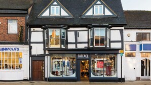 En traditionell byggnad med korsvirkesfasad, där det finns en butik som heter ”Fatface” på bottenvåningen.