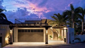 Une maison moderne dotée d’un garage, d’un patio couvert et d’un escalier menant à un deuxième étage.