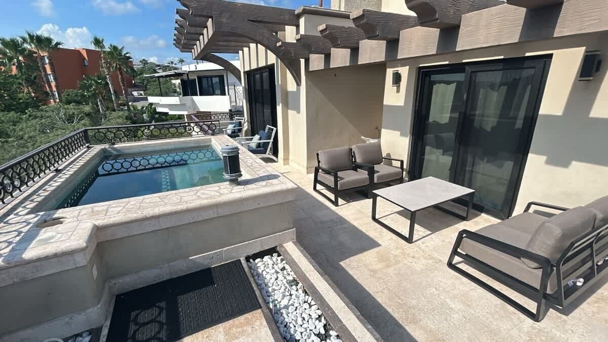 A rooftop pool area with a hot tub, lounge chairs, and a pergola.