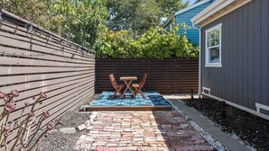 A patio area with a brick floor, a wooden table and chairs, and a blue patterned rug. - Peaceful 3-bedroom house in charming Berkeley perfect for your stay incl Parking (Berkeley)