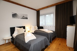 A hotel room with two beds, a small table, a TV, and a painting on the wall. - Apartment Near the Kitzski Area (Jochberg)