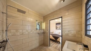 Een moderne badkamer met een inloopdouche, een grote spiegel en een apart gelegen wastafel.