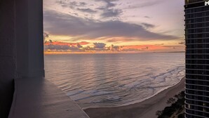 A view of a beach with a sunset, a building, and a clear sky. - Spacious 4-bedroom apartment in brilliant Surfers Paradise with AC (Surfers Paradise)