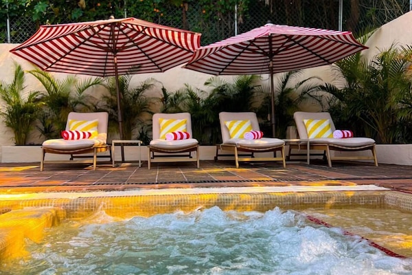 Una piscina al aire libre, sombrillas, sillones reclinables de piscina