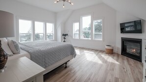 Une chambre à coucher avec un grand lit, un télescope, une cheminée et de nombreuses fenêtres.