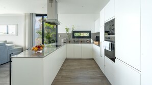 Una cocina moderna con una isla central, electrodomésticos integrados y vistas al exterior.