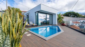 Un área de piscina moderna al aire libre con una vista despejada del cielo y edificios circundantes.