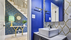 A bathroom with a blue wall, a white sink, and a mirror. - Game Room | Family House | Close to Buford Highway (Chamblee)