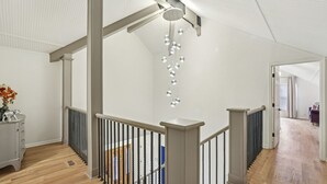 A modern interior with a wooden floor, a staircase with a metal railing, and a hanging light fixture. - Game Room | Family House | Close to Buford Highway (Chamblee)