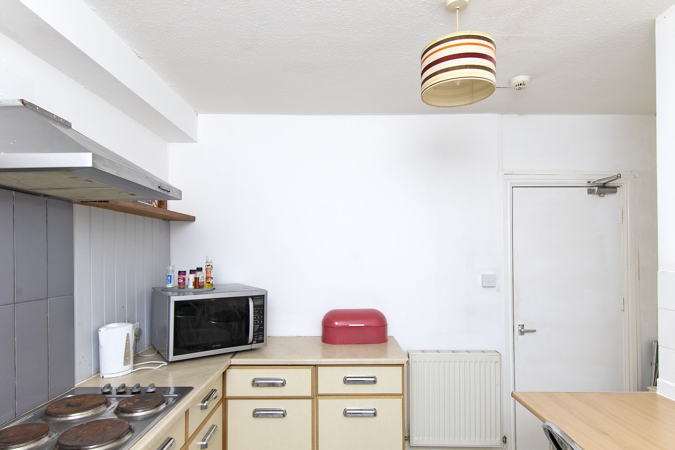 A kitchen with a microwave, stove, cabinets, and a red appliance on the counter.