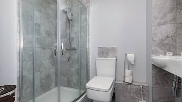A modern bathroom with a glass-enclosed shower, a white toilet, and a marble-tiled wall.