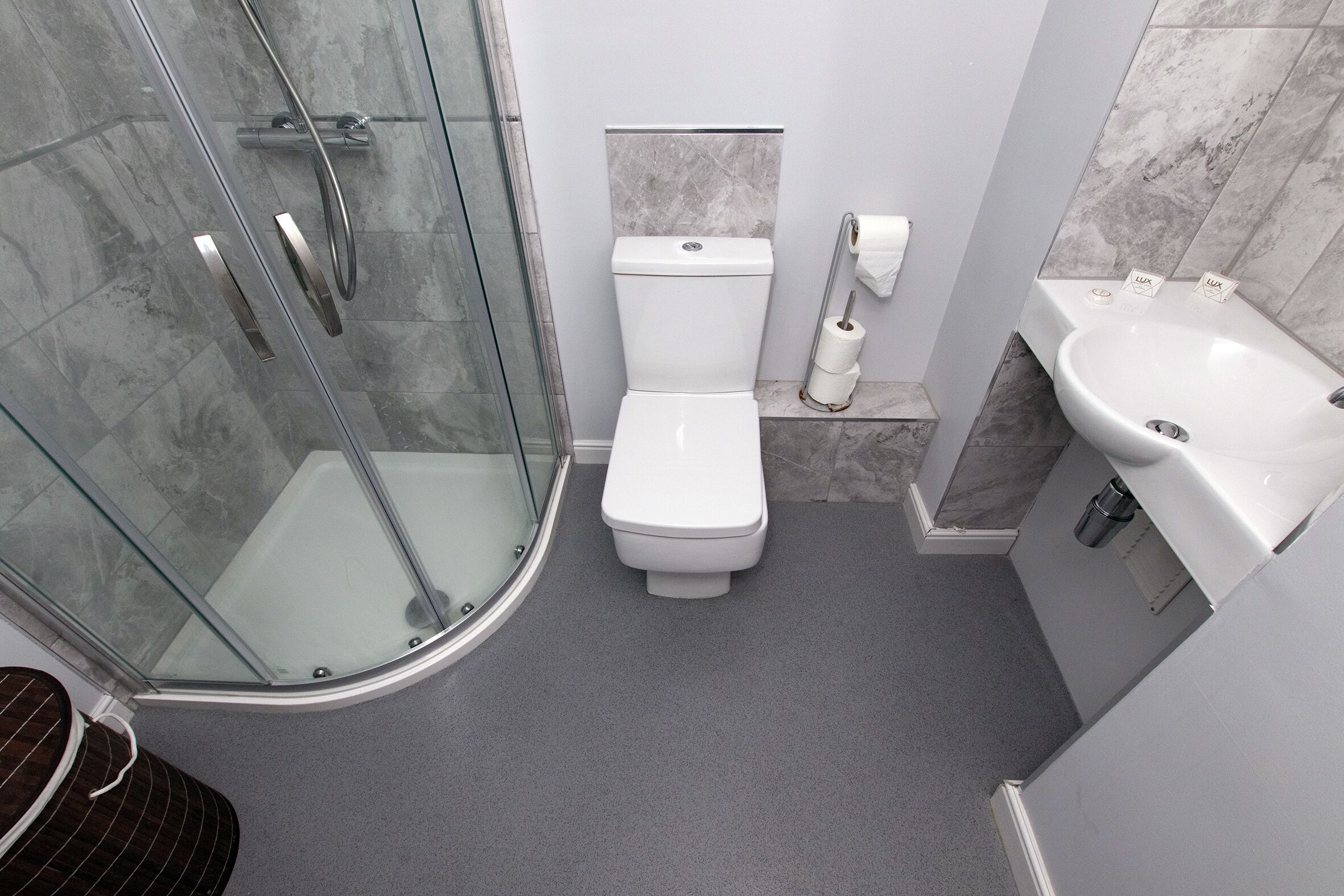 Un baño moderno con cabina de ducha de vidrio, inodoro y lavamanos.