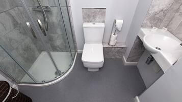 Un baño moderno con cabina de ducha de vidrio, inodoro y lavamanos.
