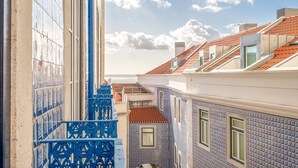 Un estrecho callejón con edificios que presentan fachadas de azulejos azules y blancos, una reja de hierro azul y una vista despejada del cielo y las nubes.