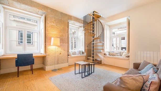Una sala de estar moderna con una escalera espiral, ventanas amplias y una zona de estar acogedora.
